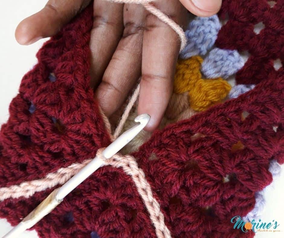Insert your hook through the back loop of the corner stitch in the join on the left of the center flap.