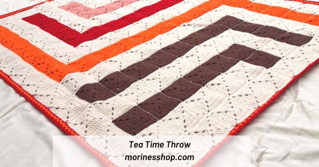 Cozy up under the Tea Time Throw, a mindful and relaxing crochet project that produces a gorgeous graphic solid granny square blanket.